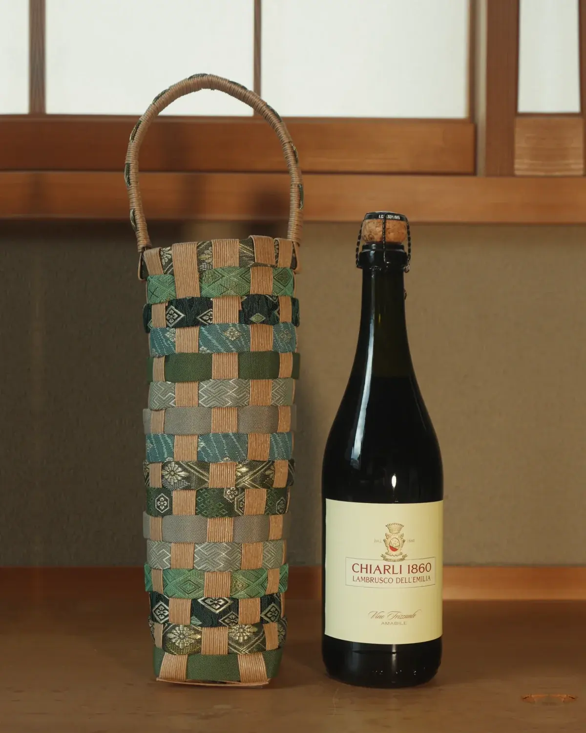 Koke — Moss, sage and grey in narrow rows, under a pale woven handle.