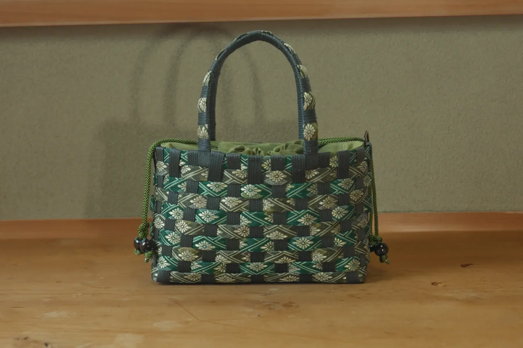Kago — Woven like a basket in green and gold, with a drawstring lining.