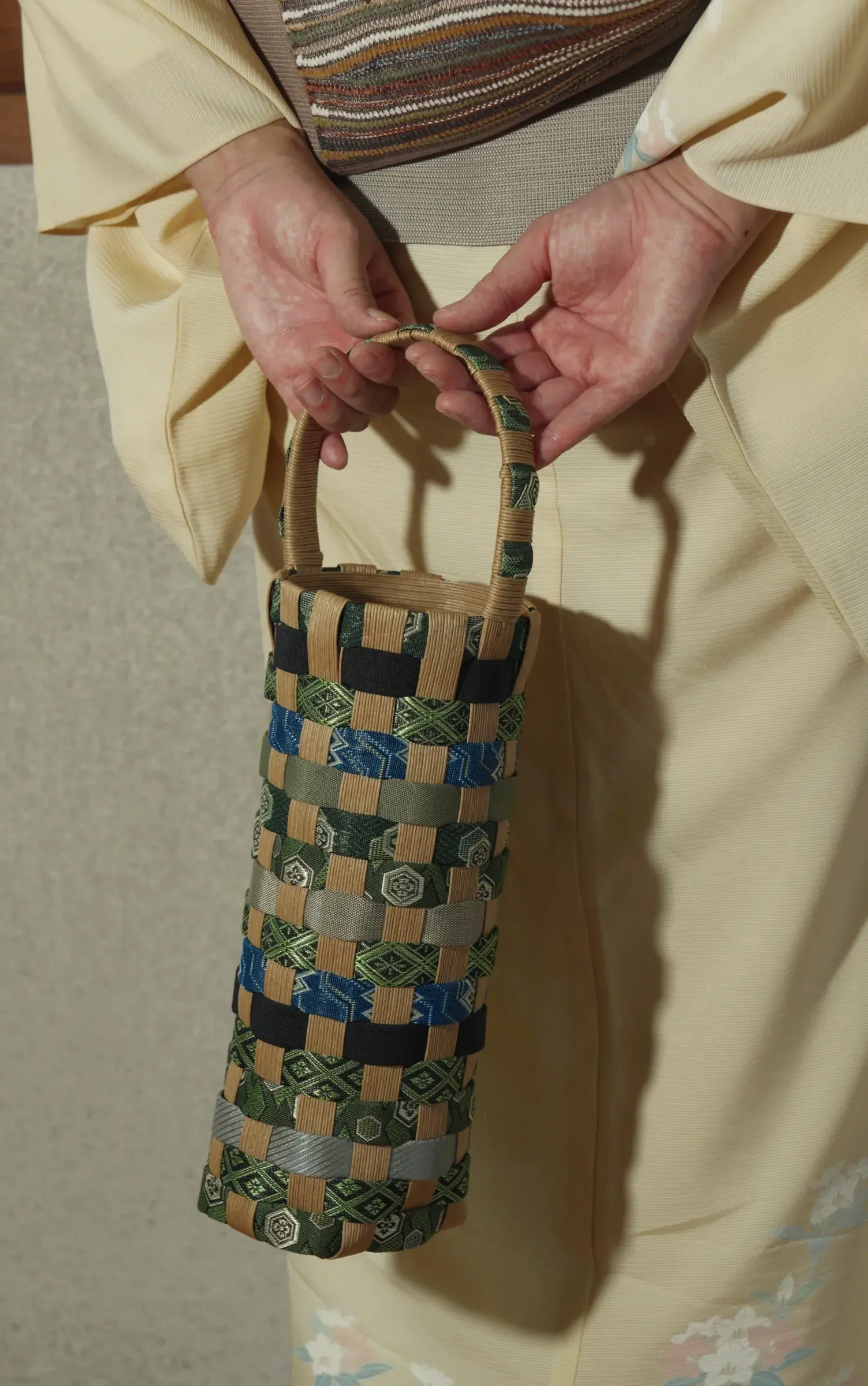 Hands holding a woven bottle bag by its handle